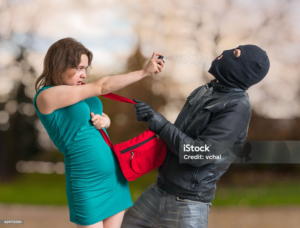 Self defense concept. Young woman is spraying with pepper spray on thief.